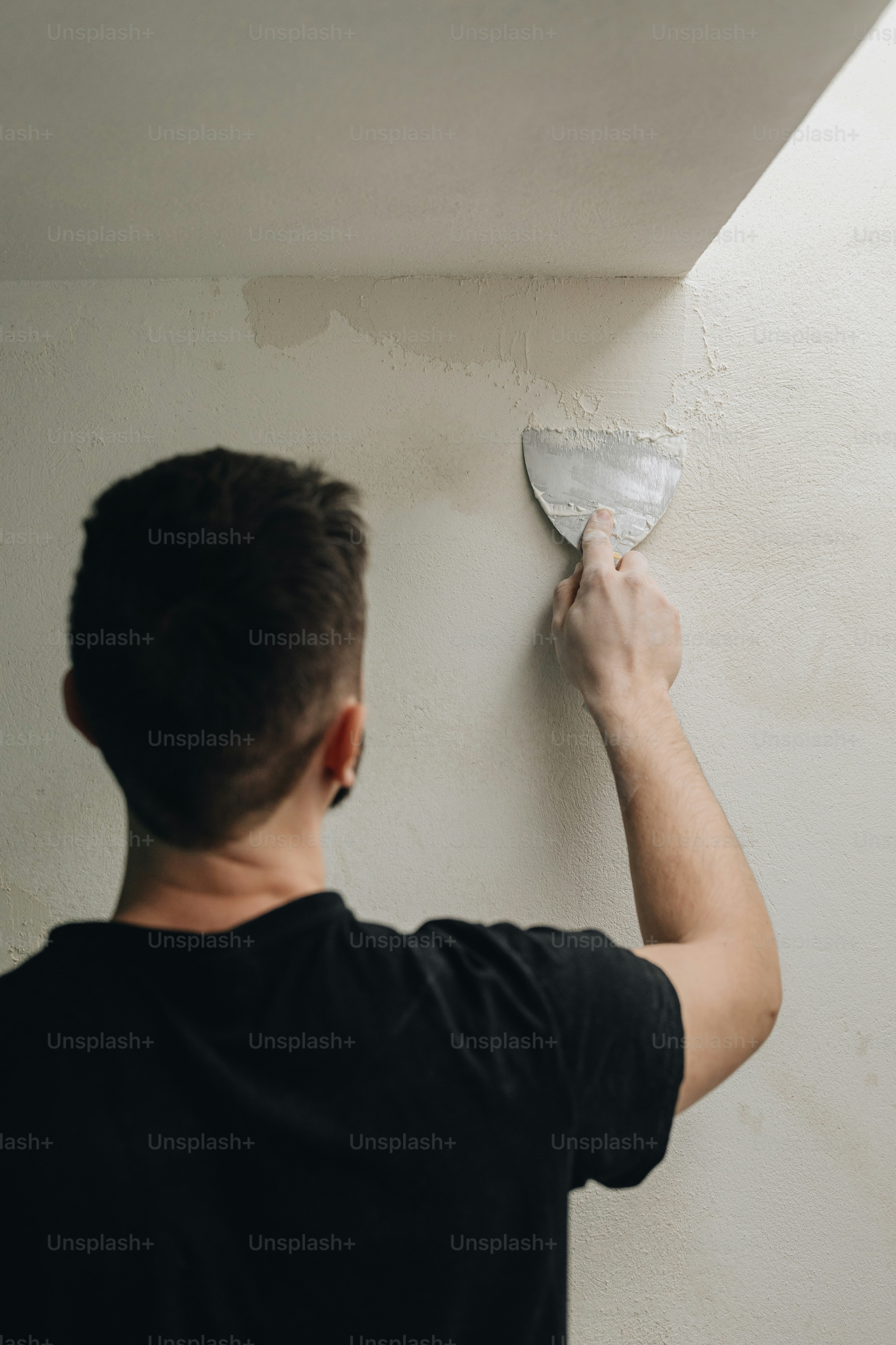 a man plastering a wall with a paint roller