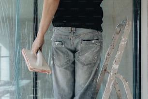 a person standing on a stepladder holding a paint roller