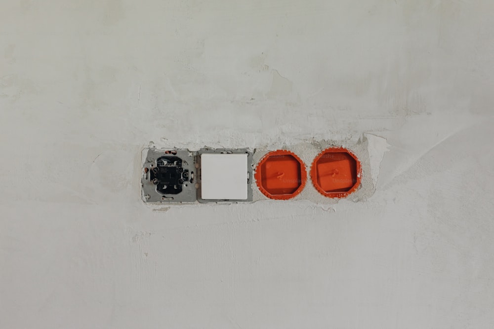 Un par de luces rojas sentadas encima de una pared blanca