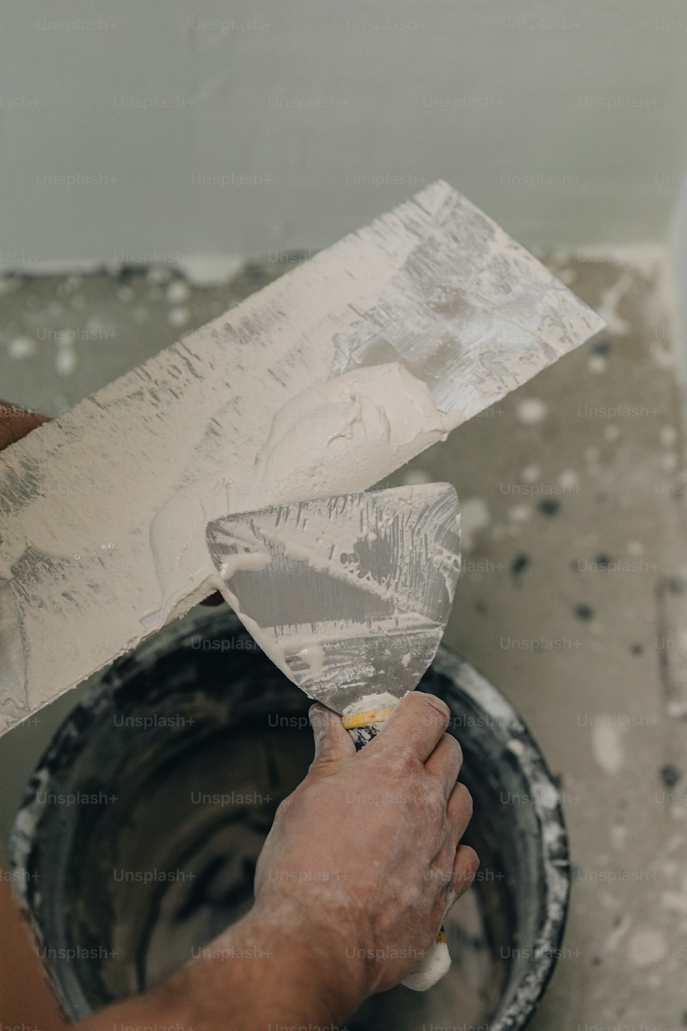 Un homme peint un mur avec de la peinture blanche