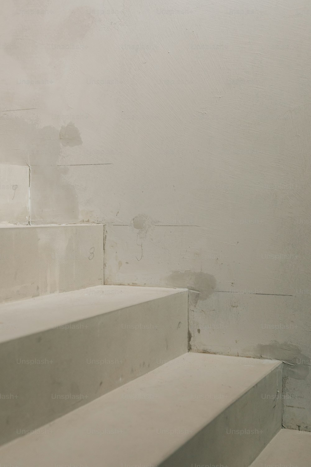 um conjunto de escadas brancas que levam até uma parede branca