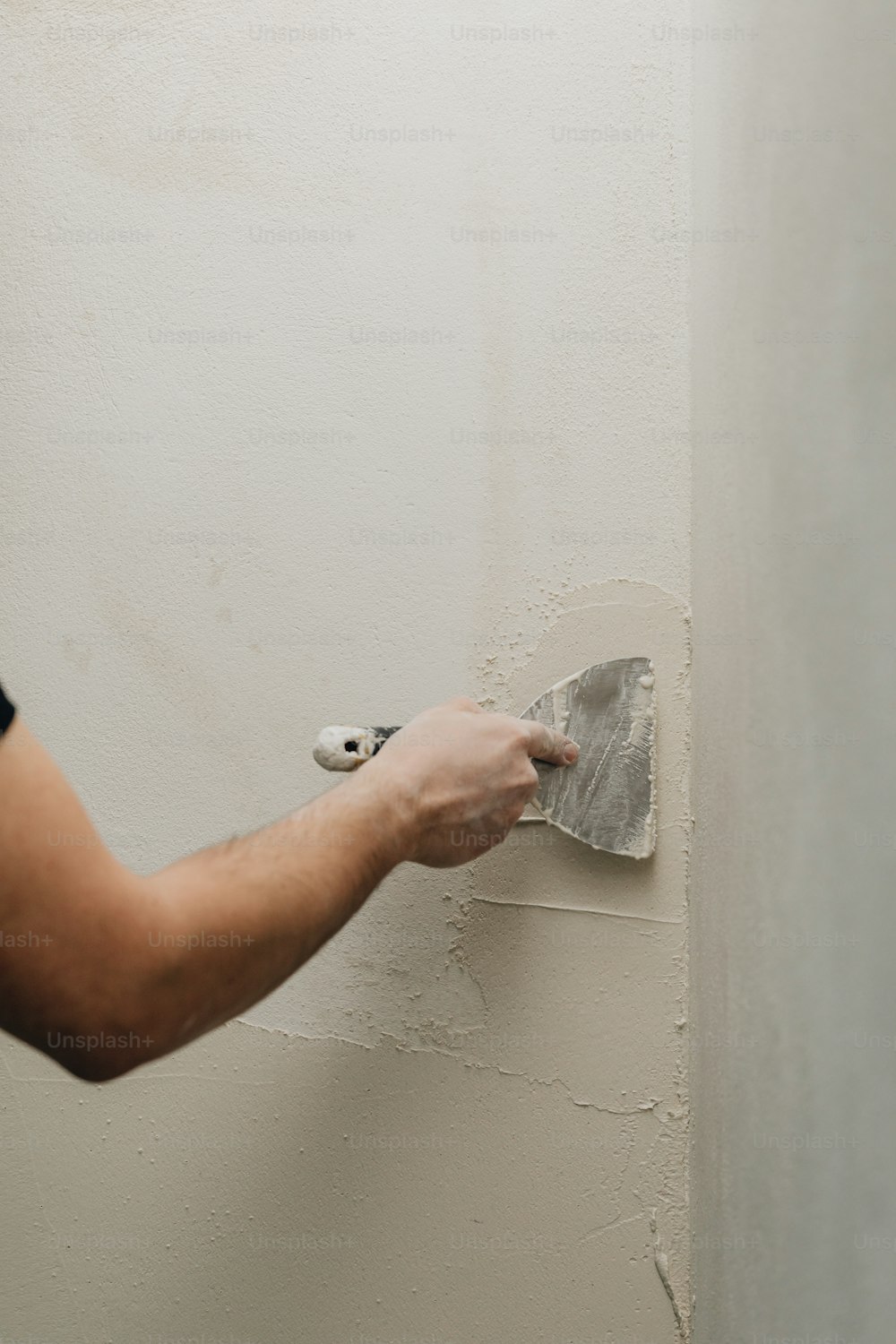 eine Person, die einen Farbroller benutzt, um eine Wand zu streichen