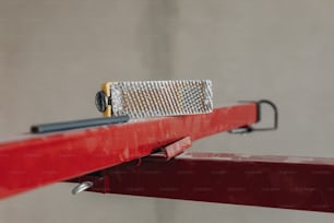 a close up of a metal object on a red rail