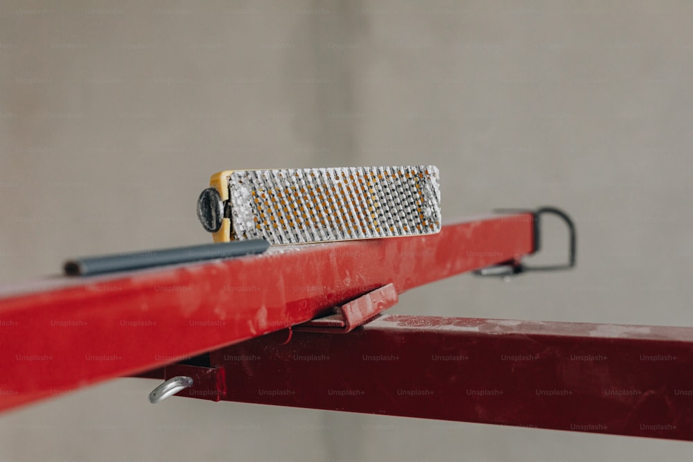 Un primer plano de un objeto metálico en un riel rojo