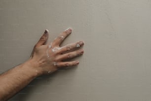 壁に手を伸ばす人の手