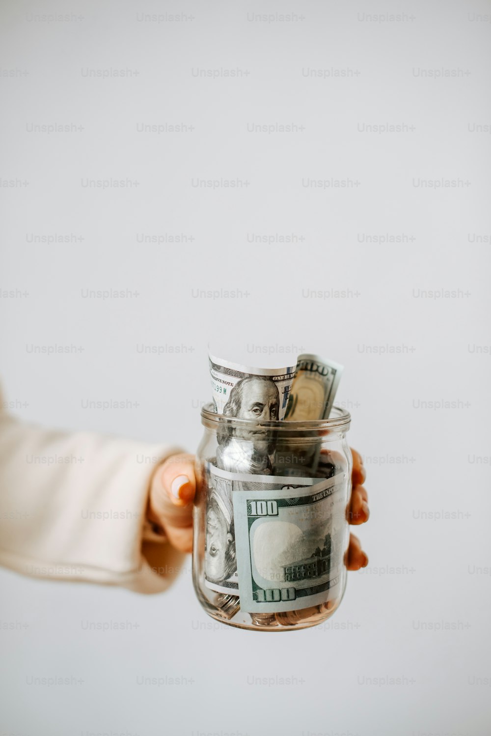 a person holding a glass jar filled with money