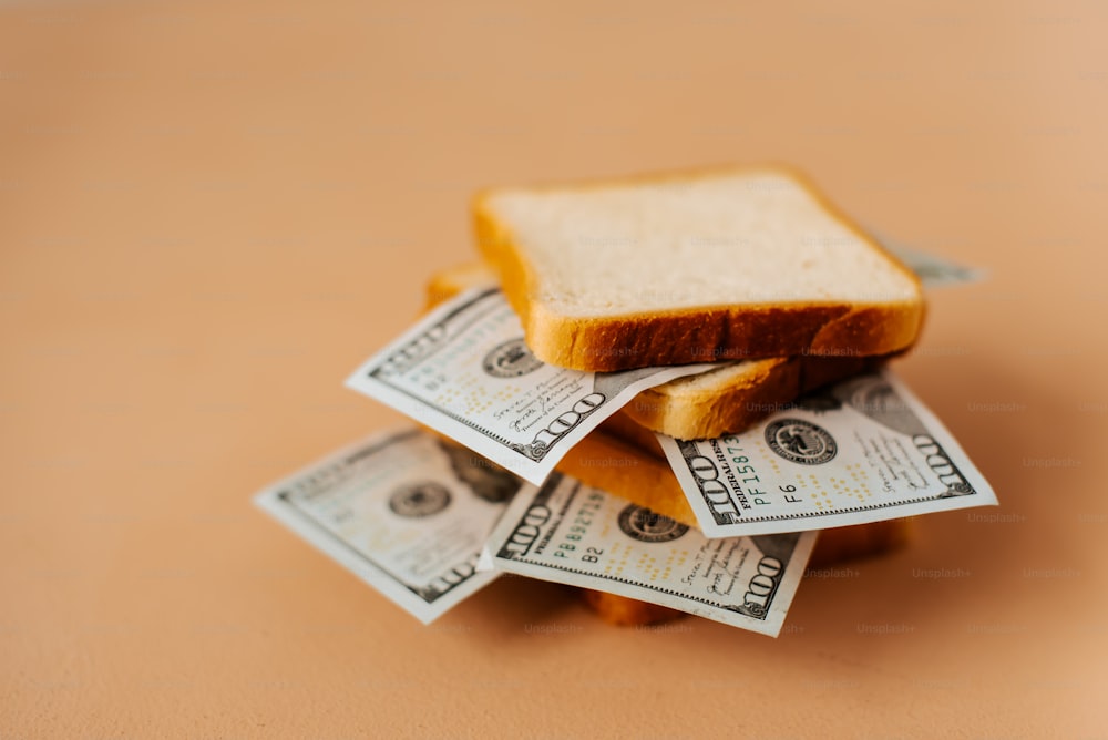 a pile of money sitting on top of a piece of bread