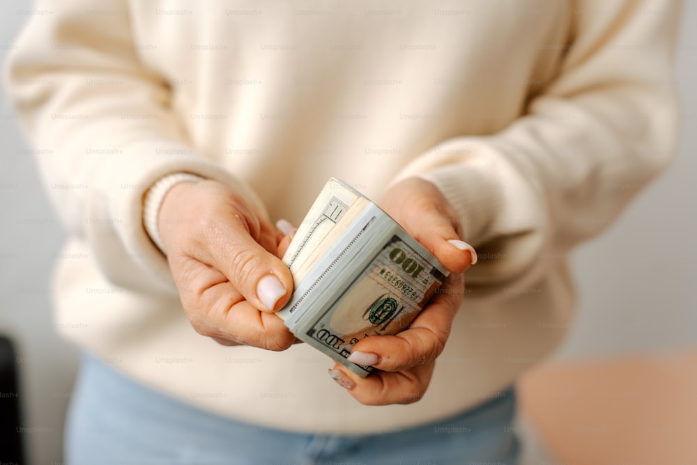 uma mulher segurando uma pilha de dinheiro em suas mãos