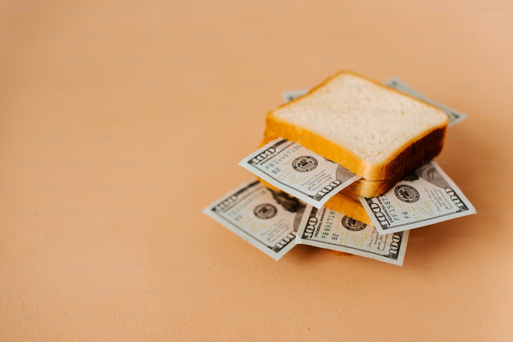 um sanduíche torrado sentado em cima de uma pilha de dinheiro