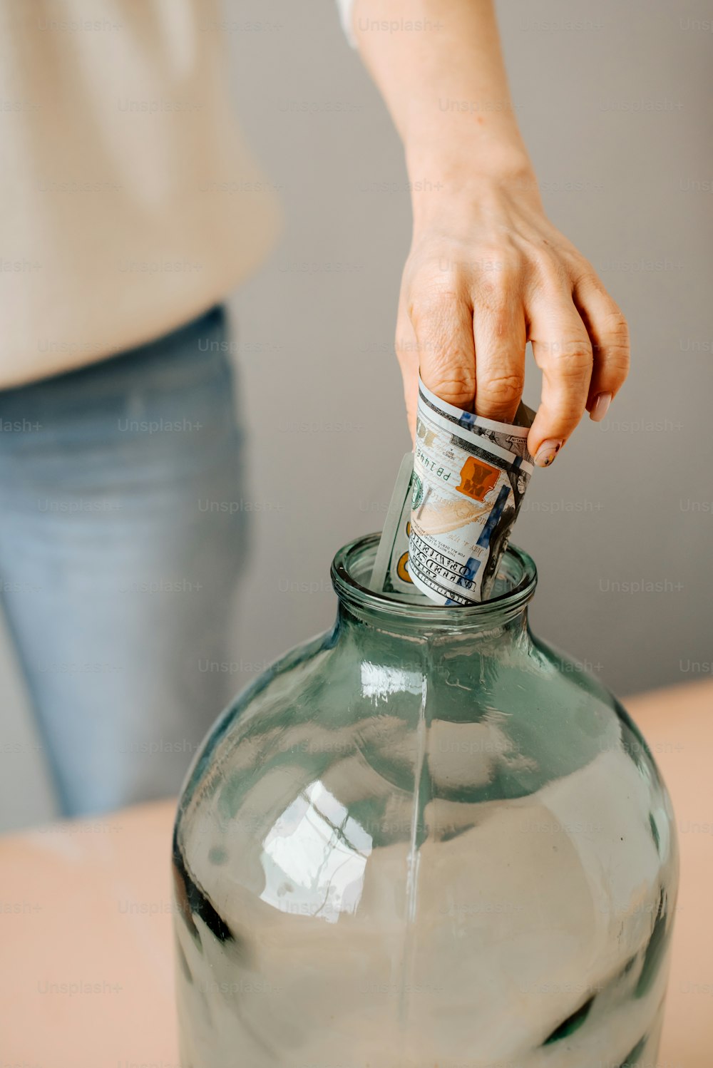 a person putting money into a glass jar