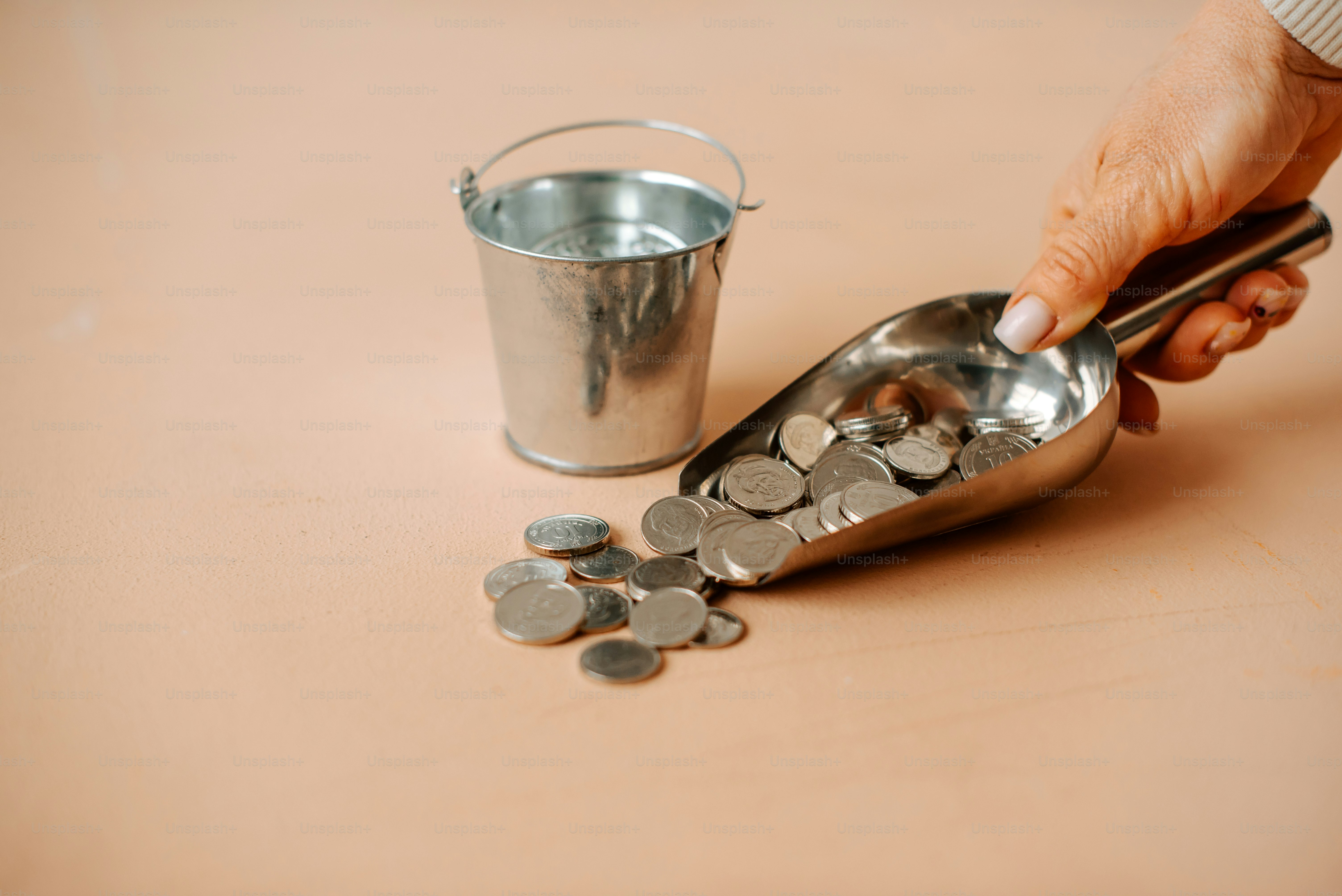 uma pessoa colhendo moedas de um balde de metal