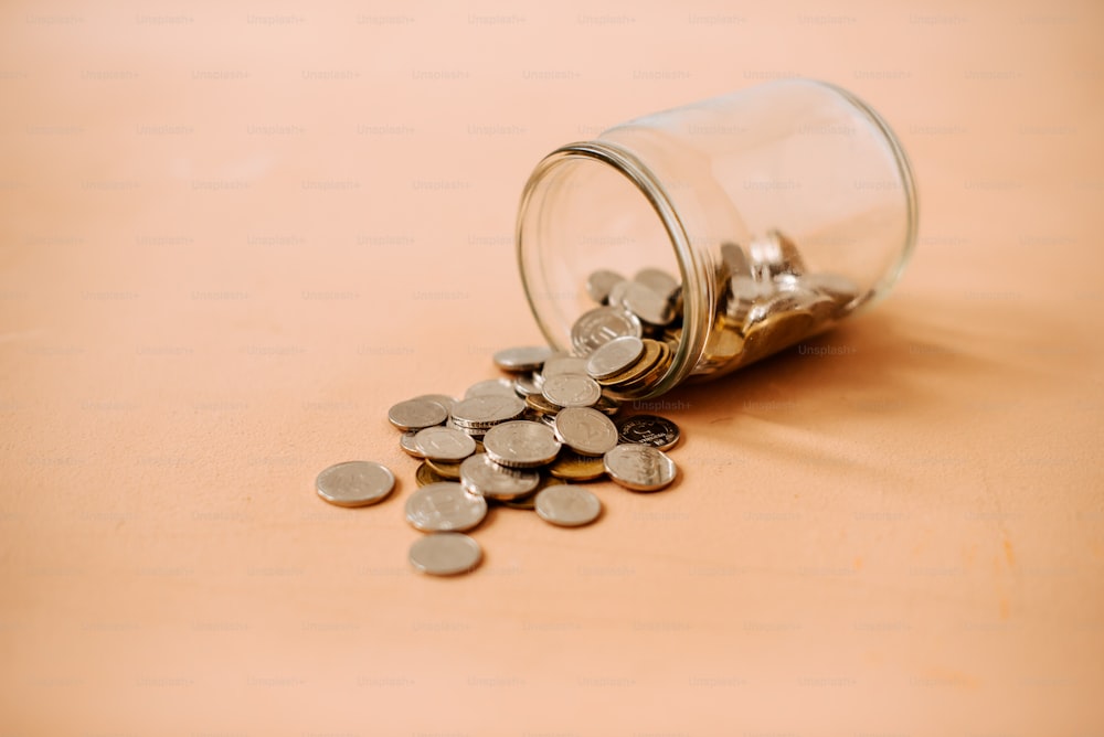 un bocal en verre rempli de pièces de monnaie sur le dessus d’une table