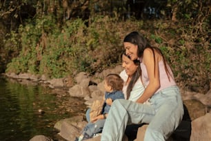 a woman sitting on a rock next to a little boy