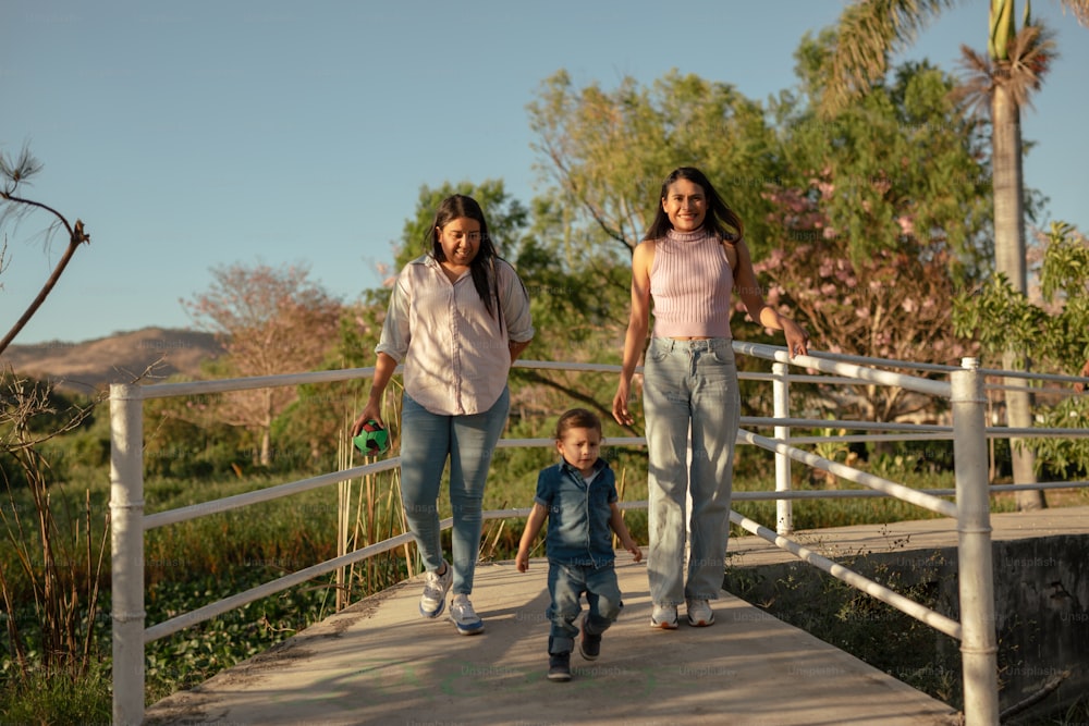 uma mulher e duas crianças caminhando através de uma ponte