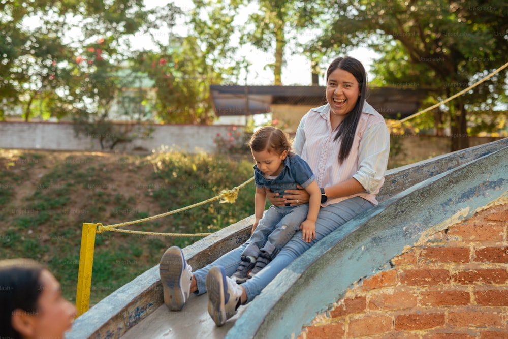 a woman sitting on top of a slide with a child