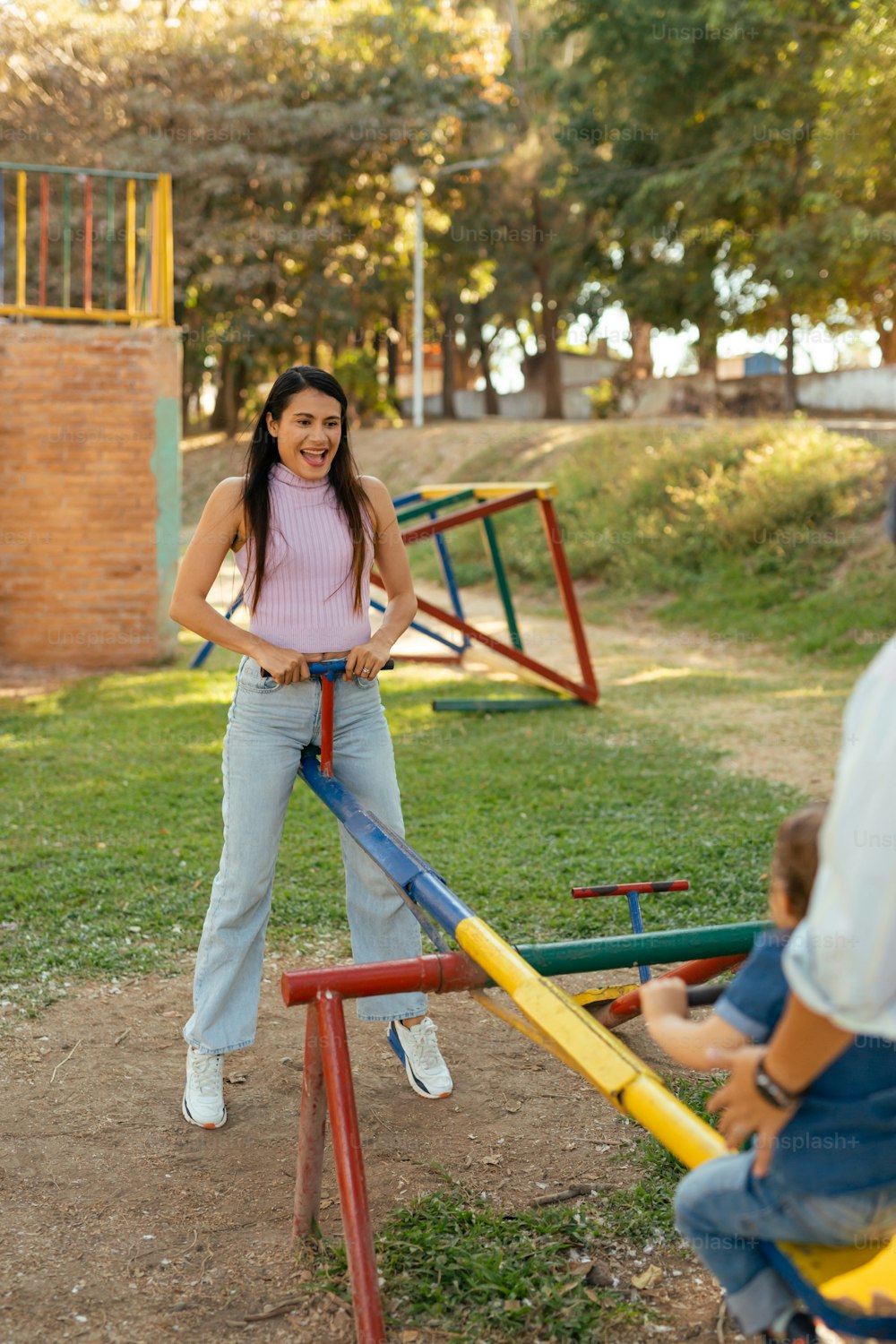 Eine Frau, die neben einem Kind auf einem Spielplatz steht