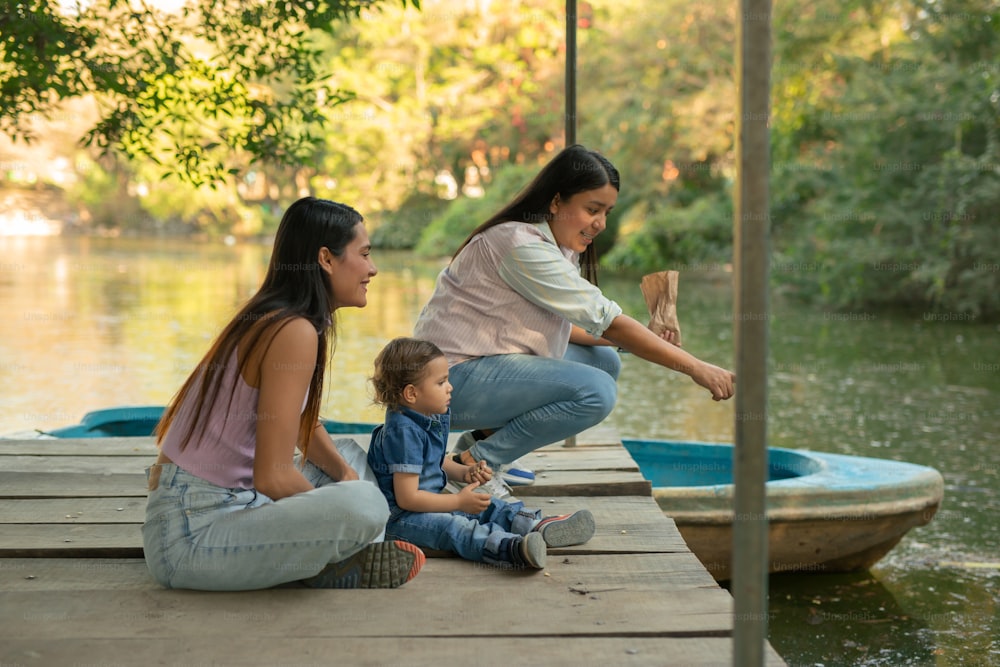 two women and a child sitting on a dock