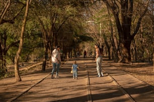 a group of people walking down a tree lined road