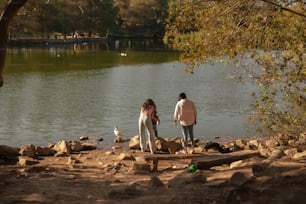 a couple of people standing next to a body of water