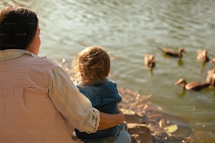 a woman and a child looking at ducks in the water