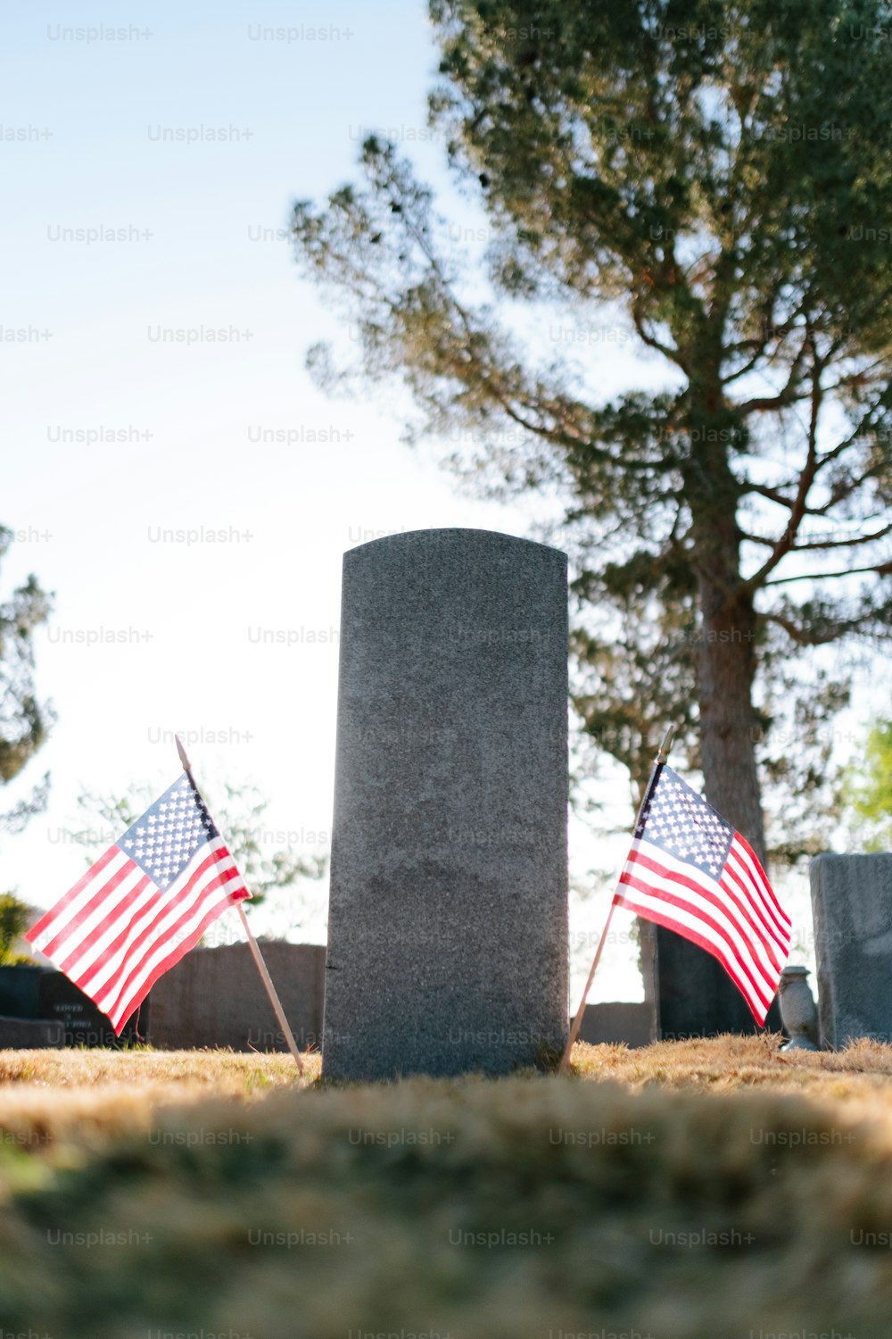 two american flags on a grave in a cemetery