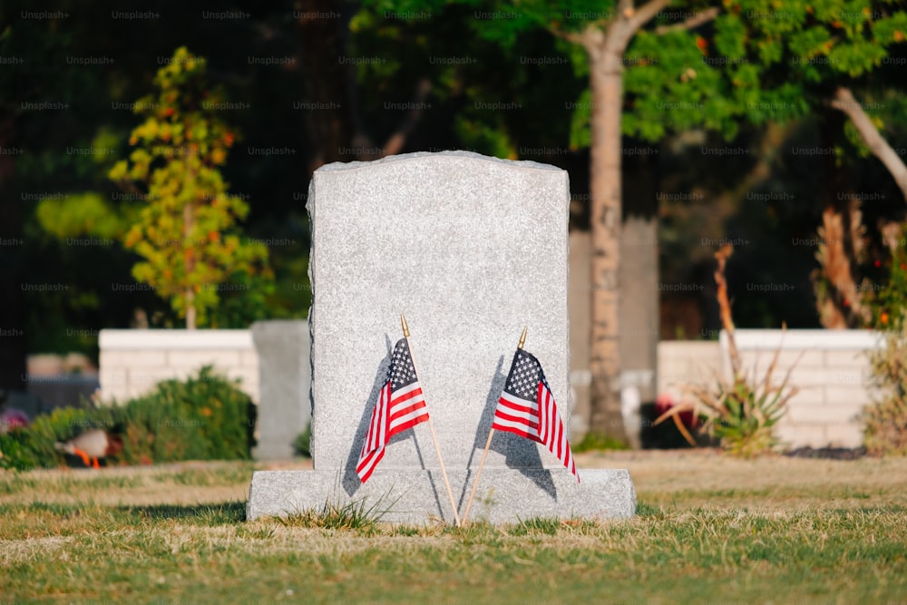 two american flags are placed in front of a grave