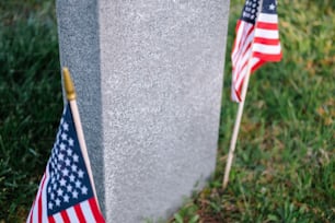 two american flags are placed next to a grave