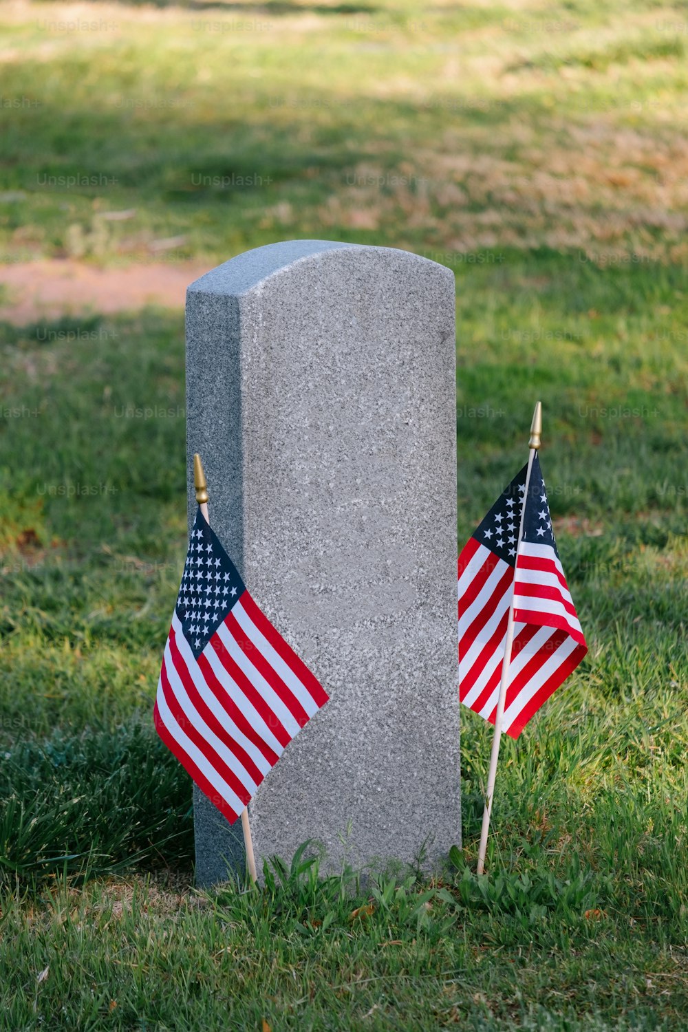two american flags are placed next to a grave
