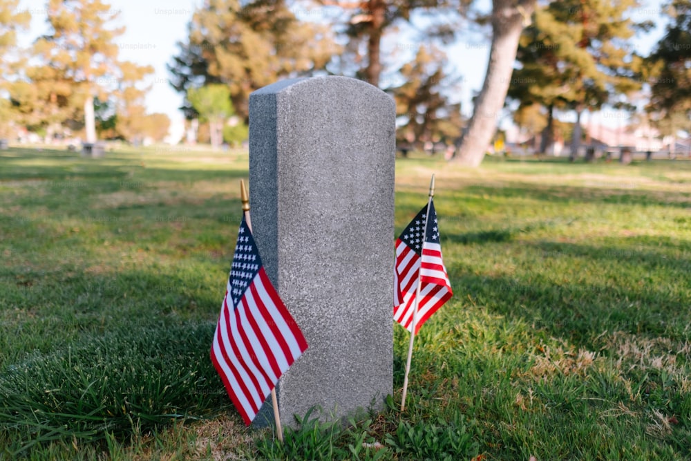 duas bandeiras americanas são colocadas ao lado de um túmulo