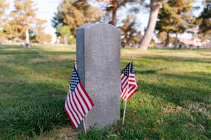 two american flags are placed next to a grave