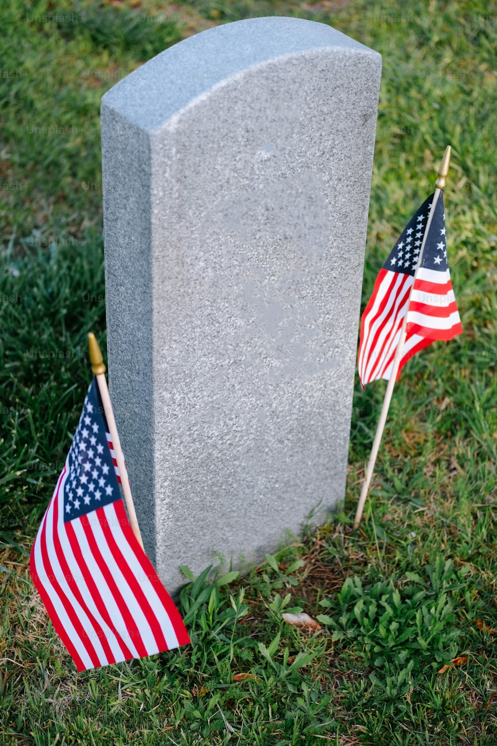 a grave with two american flags next to it