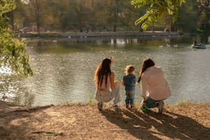 uma mulher e duas crianças olhando para um lago