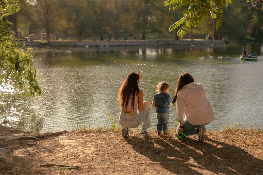 a woman and two children looking at a lake
