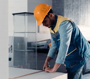 a man in a hard hat cutting a piece of wood