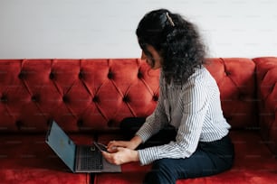 a woman sitting on a couch using a laptop computer