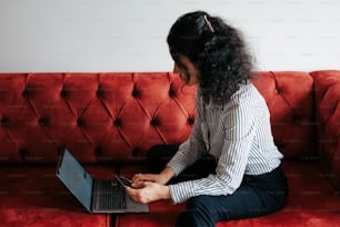 eine Frau, die mit einem Laptop auf einer Couch sitzt