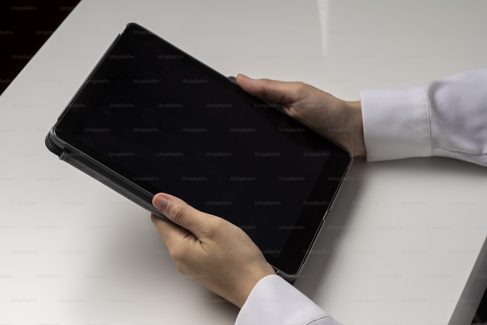 a person holding a tablet on a white table