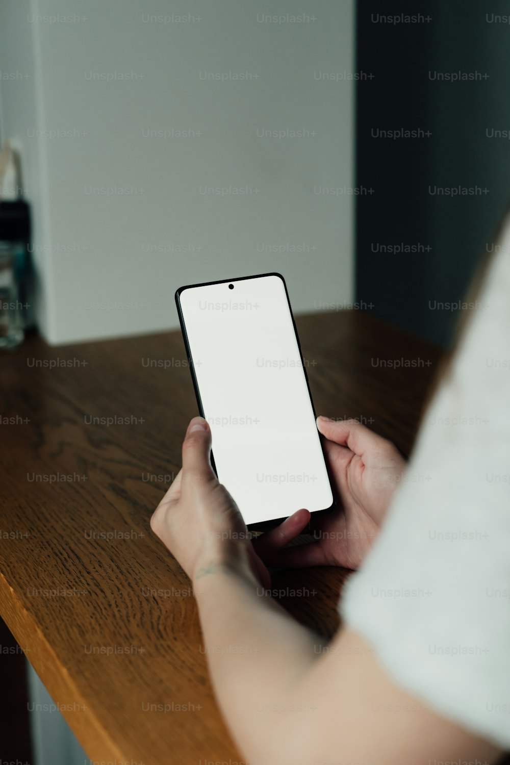 a person holding a cell phone on a wooden table