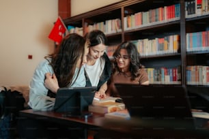 three women looking at a laptop in a library