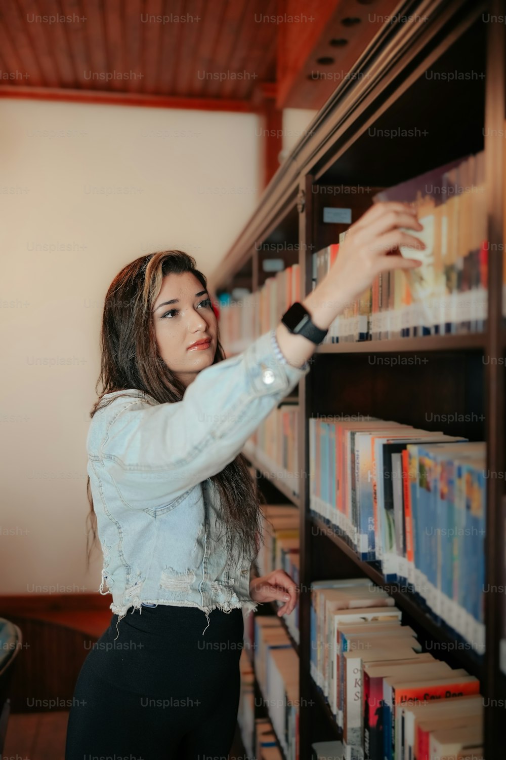 a woman reaching for a book in a library