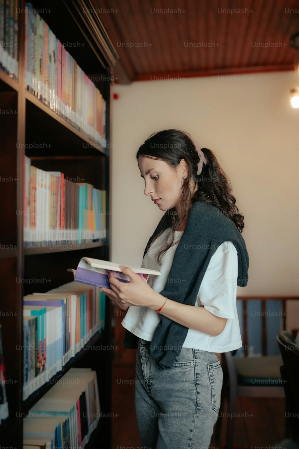 a woman is reading a book in a library