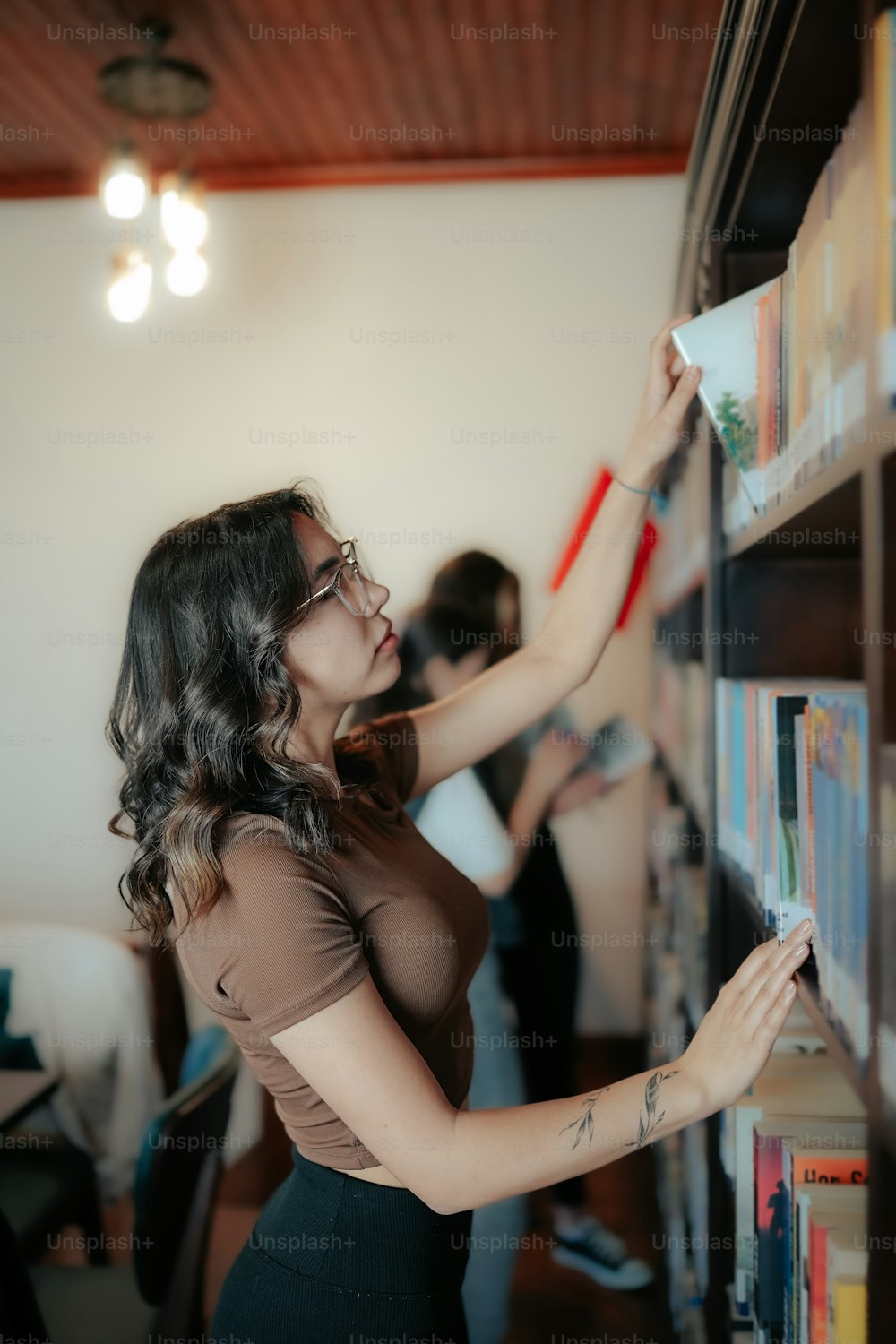 Una mujer mirando un libro en un estante