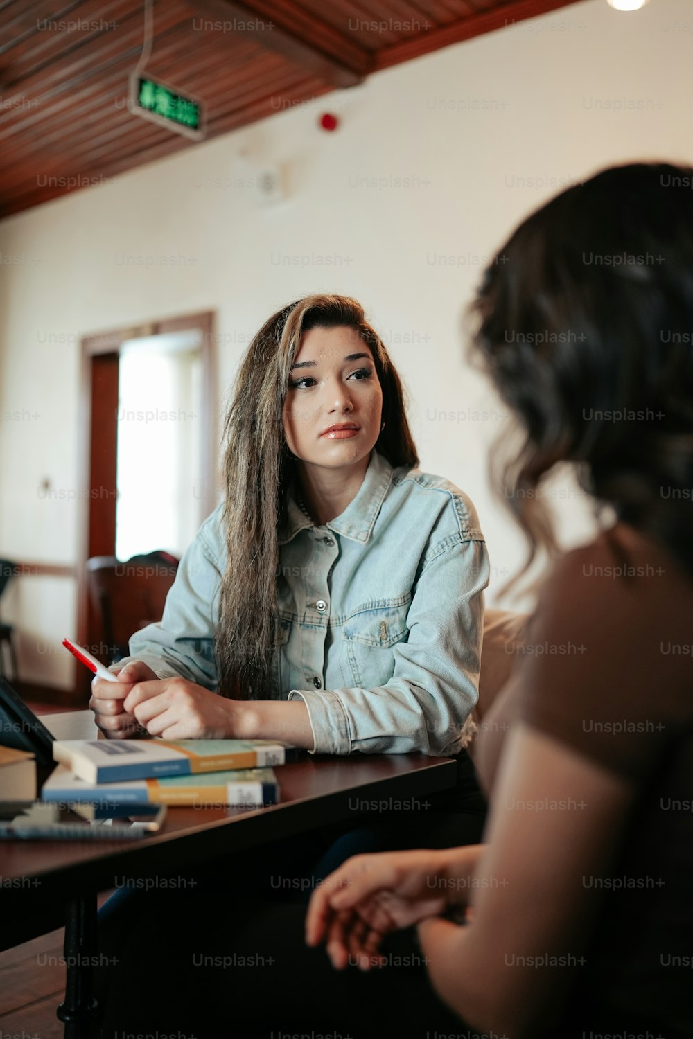 a woman sitting at a table with a pencil in her hand