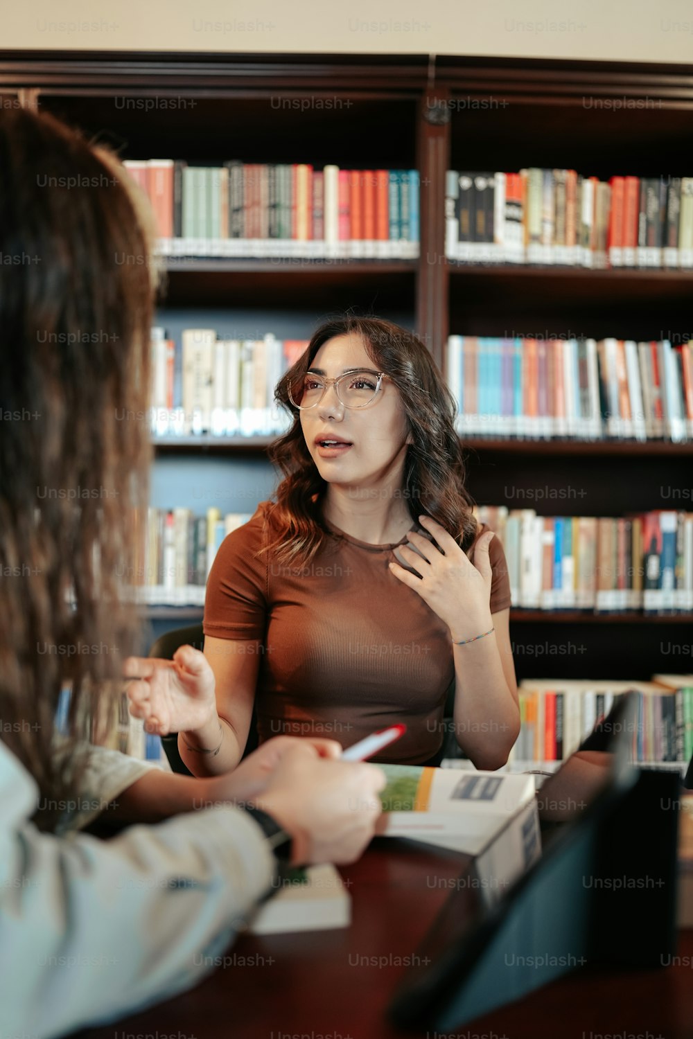a woman talking to another woman in a library