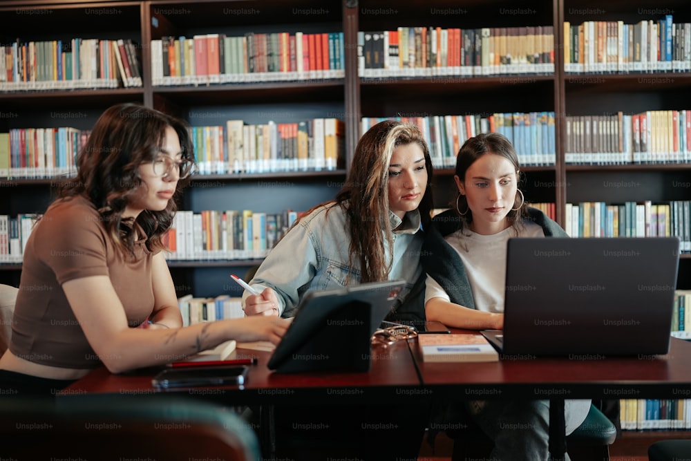 a group of women sitting at a table in front of a laptop computer