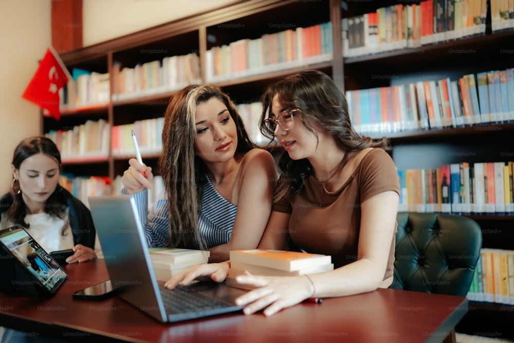 duas meninas olhando para um laptop em uma biblioteca