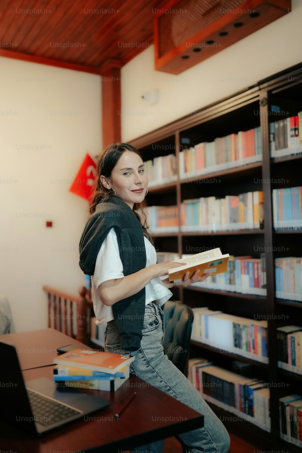 a woman standing in front of a bookshelf holding a book