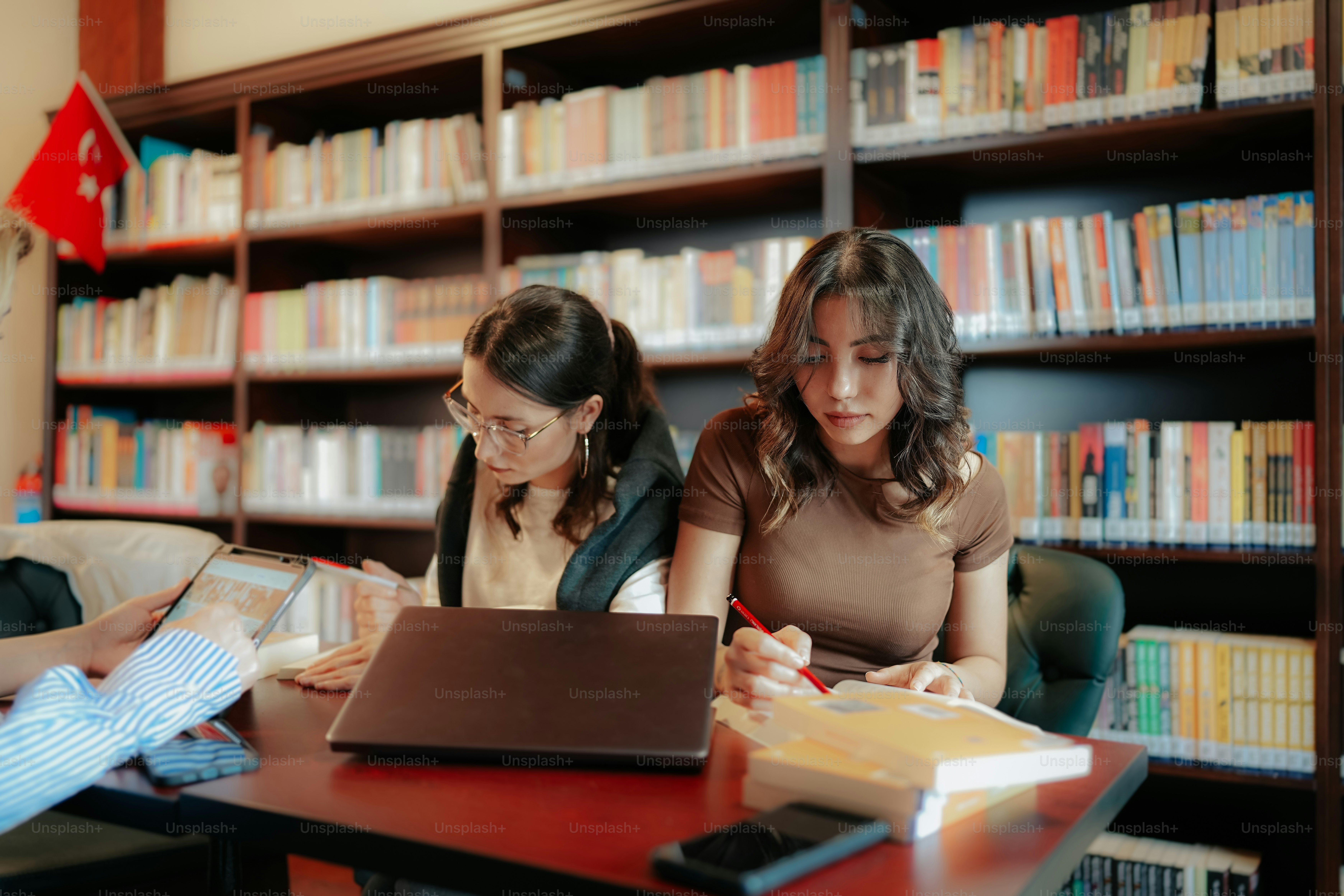 a couple of women sitting at a table in front of a laptop computer