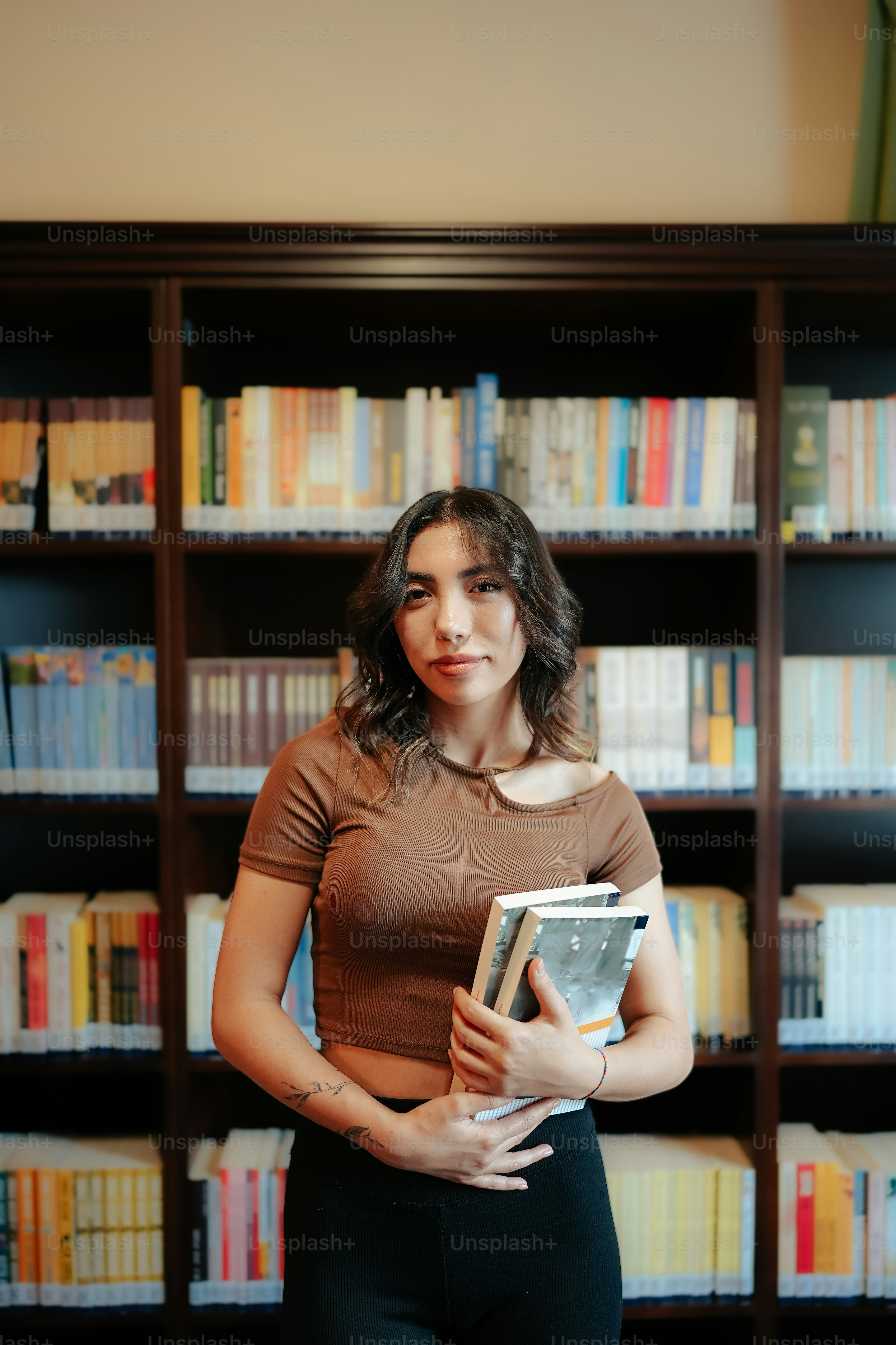 a woman standing in front of a bookshelf holding a book