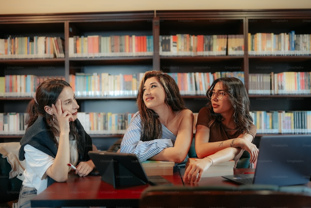 a group of women sitting at a table in front of a laptop computer